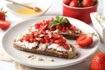 Bruschettas with ricotta cheese, chopped strawberries and mint on white wooden table, closeup