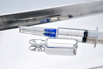 Syringes with needles and an ampoule in a stainless steel medical tray.