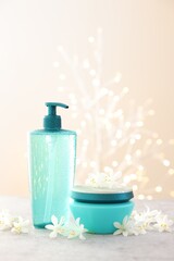Cosmetic products and beautiful jasmine flowers on grey table