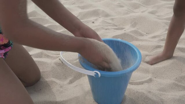 Slow motion of a young girl playing in the sand with a bucket to build a sand castle