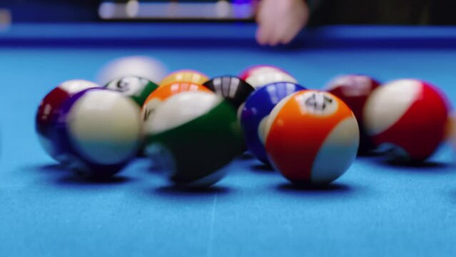 Close up. Woman breaking racked pool balls in eight-ball on billiard table