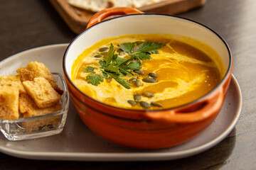 Pumpkin cream soup in bowl. Soup and croutons in the restaurant. Food serving