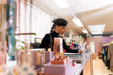 Serious multiracial woman writing checklist in retail store clothes at the counter