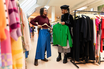 Lady customer shopping in modern clothing store, retail sales associate assists client