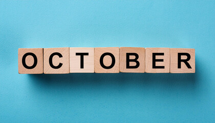 Wooden cubes with text OCTOBER on blue backdrop. Autumn season. Month of year. Close-up. Flat lay