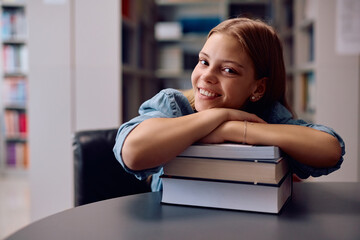 Portrait of happy female student in library looking at camera.