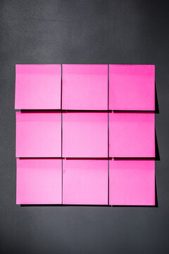 Pink sticky notes on dark gray magnet board