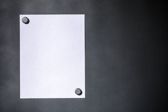 Blank white letter size paper on dark gray magnet board