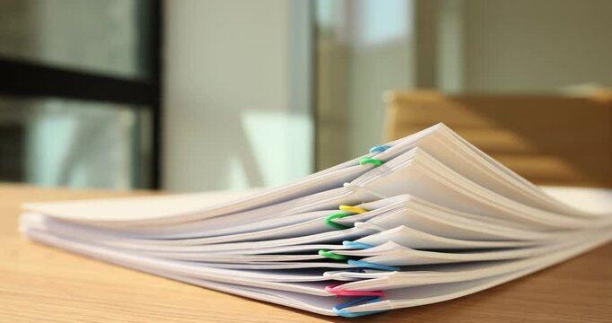 Time lapse of papers with multi-colored clips disappearing from wooden table in office. Stack of documents and accounting papers at secretary workplace