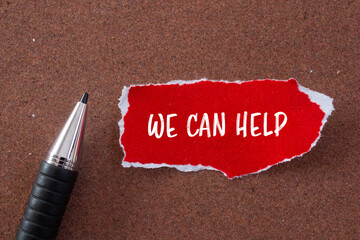 We can help message written on ripped torn red paper and a pen with brown background. Conceptual we...