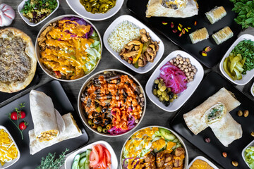 Vibrant Mediterranean feast featuring an array of dishes including wraps, salads, grilled meats, and fresh vegetables. This colorful spread showcases the rich flavors and diverse ingredients.