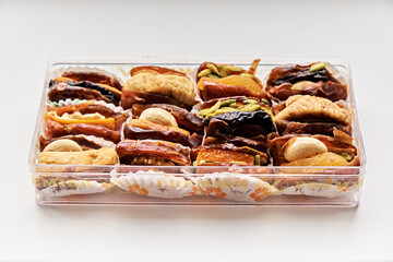 Twelve stuffed dates in a box on a white background. Dates with nuts, a sweet dessert.