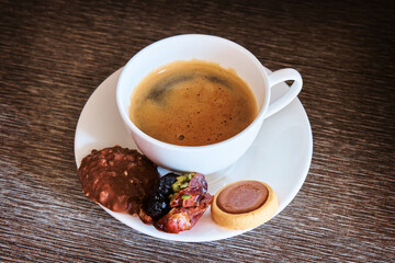 A cup of fragrant morning coffee with cookies on the table. White cup with freshly brewed coffee with dessert on dark table. Selective focus