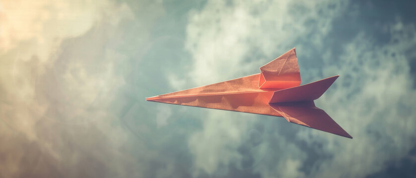 A vividly colored paper airplane against a cloudy sky symbolizes dreams taking flight, blending simplicity with aspirational imagination.