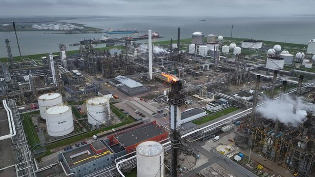 Aerial view of a chemical plant at sunset. Drone shot. Curling fire and cumin smoke filling the sky. Smoking chimneys from the factory. Chimneys of an oil refinery at sunrise pollute the environment