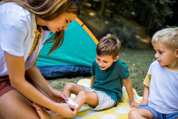 Mom putting a bandage on a little boy. Boy hurt himself on a camping.