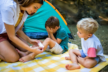 Mom putting a bandage on a little boy. Boy hurt himself on a camping.