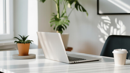 A laptop is on a table next to a potted plant