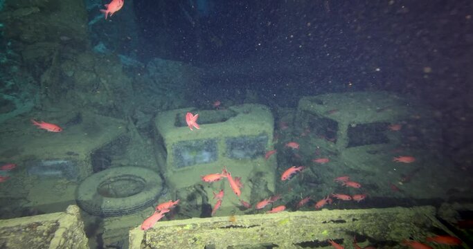 Divers explore the wreck of the SS Thistlegorm. Top diving wreck dives. Swimming over motorbikes and other cargo in hold of Thistlegorm shipwreck in the Red Sea, Sharm el Sheikh, Egypt.