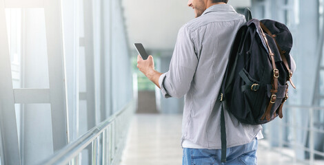 Unrecognizable Man Walking In Airport Terminal And Using Smartphone, Browsing Internet Or Switching Flight Mode, Cropped Image, Panorama