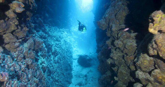 Group of divers swimming in an underwater cave canyon. Diving instructor and group students in underwater exploration. The instructor teaches the students. Scuba diving training and education.