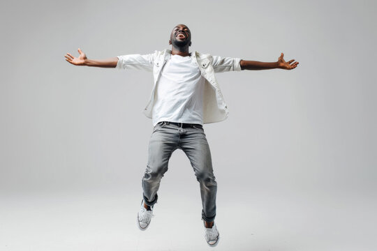 a photo of a happy african american man in casual wear jumping on a grey studio background