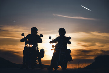 Silhouette of two rider on a motorbike admiring sunset