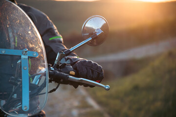 Biker driving a motorcycle rides along the asphalt road in sunset.