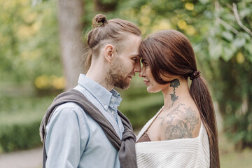 Love, hug and happy with couple in park for romance, bonding and summer vacation. Loving young couple hugging and smiling together on nature background. Beautiful girl with tattooed body outdoor.