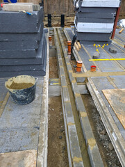 Beam and block floor construction with insulation boards and thermal bridging blocks on a concrete foundation with steel columns on a construction site.