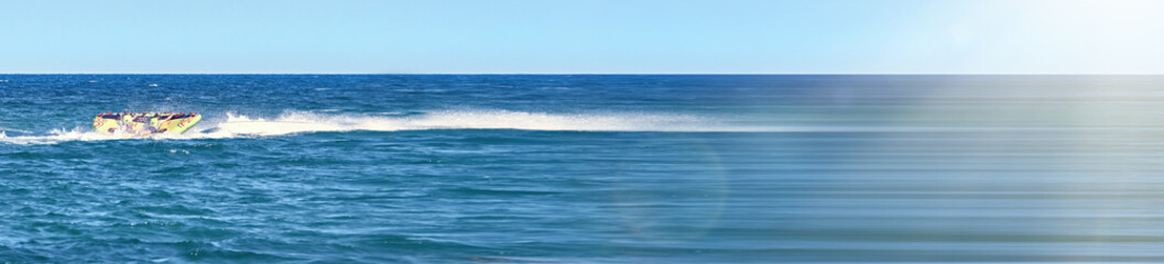 Fototapeta premium Banner of colorful inflatable water attraction that is towed across the ocean, creating a dynamic and vibrant scene of water recreation and summer fun.