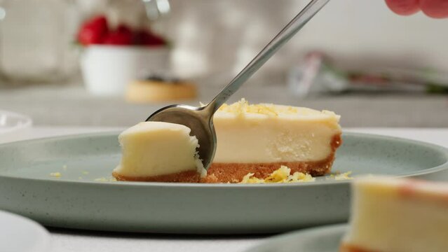 Eating classic dessert cheesecake by spoon close-up macro. Cheesecake is a dessert made with a soft fresh cheese , typically cottage cheese, cream cheese, quark or ricotta, eggs, and sugar. It may