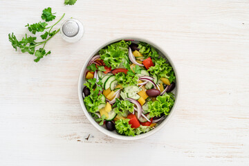 Bowl of fresh salad with vegetables on white wood rustic background