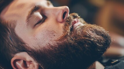 Naklejka premium A man with a long beard and mustache lies with his eyes closed in a barber shop, relaxing while waiting for a haircut.