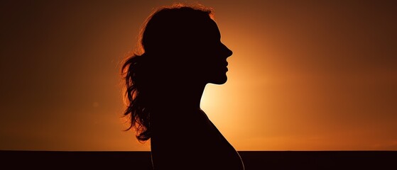 A woman's silhouette against a sunset, creating a serene and contemplative atmosphere with warm hues highlighting her profile