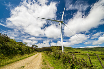 A wind turbine is standing in a field with a cloudy sky in the background. Concept of calm and...