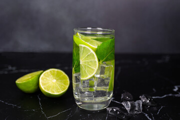 Mojito cocktail with lime, mint and ice on the black marble, dark background. Sparkling refreshing water. Space for text.  