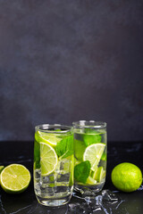 Mojito cocktail with lime, mint and ice on the black marble, dark background. Sparkling refreshing water. Space for text.  