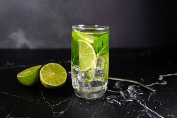 Mojito cocktail with lime, mint and ice on the black marble, dark background. Sparkling refreshing water. Space for text.  