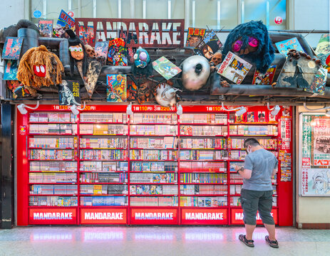 nakano, tokyo - aug 06 2023: A man from back is reading a Japanese manga in front of a shelf at Mandarake store, a pop culture related second-hand bookseller located in Nakano Broadway Shopping Street