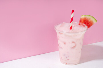 Tasty sweet watermelon milkshake or creamy slushie cocktail, garnished with watermelon slice in plastic cup, copy space