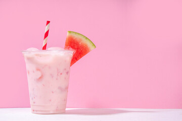 Tasty sweet watermelon milkshake or creamy slushie cocktail, garnished with watermelon slice in plastic cup, copy space