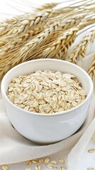A white ceramic serving bowl with a handle, filled with wheat grains, sits on a white surface next to wheat stalks