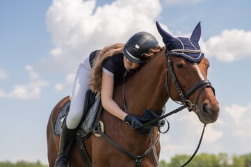 Portrait of a girl jockey hugging her horse. 