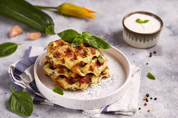 Zucchini Waffles with garlic, cheese and herbs, served with basil leaves and sour cream sauce. Healthy food.