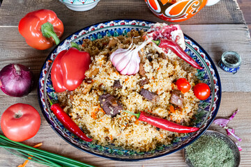 National Central Asian dish pilaf with vegetables and fruits and dishes with national ornaments.