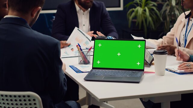 Business partners attending meeting next to greenscreen laptop, discussing the fate of the global enterprise and working on developing financial resources. Startup team address daily issues. Camera A.