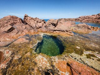 Red rocky landscape of Isola Rossa in Sardinia with clear turquoise water, in Italy