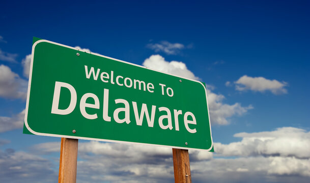 Welcome To Delaware Green Road Sign Over Blue Sky with Some Clouds.