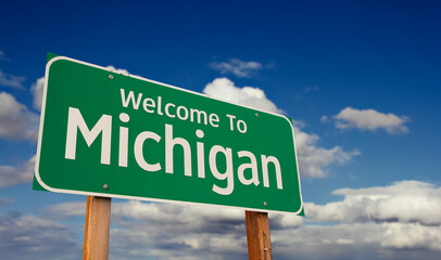 Welcome To Michigan Green Road Sign Over Blue Sky with Some Clouds.